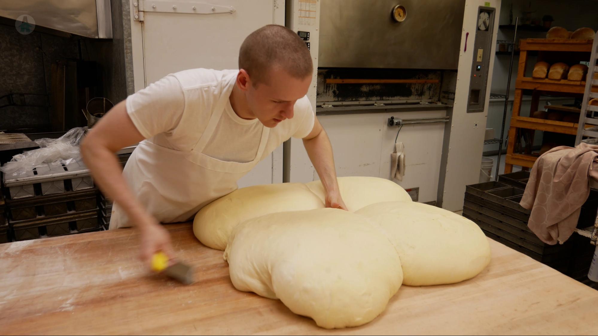 Making Donuts After rising, the donut dough is cut into four sections before it is gently patted to remove excess air and allowed to rest.